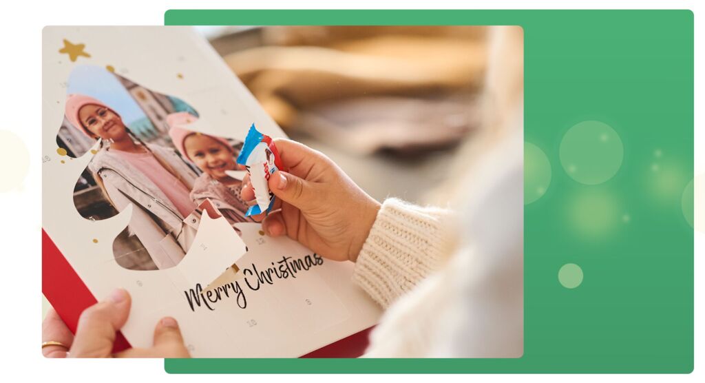Hand öffnet Adventskalender mit Foto, 'Merry Christmas' steht drauf, Kinder-Schokolade wird ausgepackt