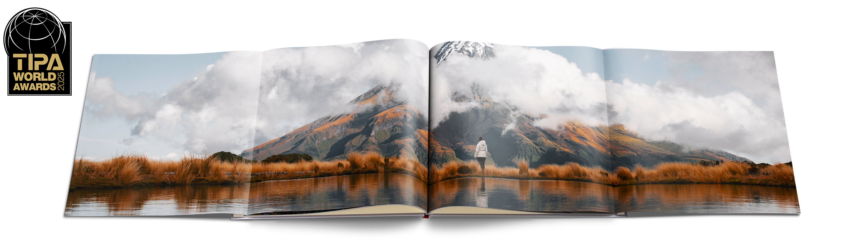 Offenes CEWE FOTOBUCH zeigt verschneiten Wald mit Rentieren und einer Hütte unter winterlichen Bäumen