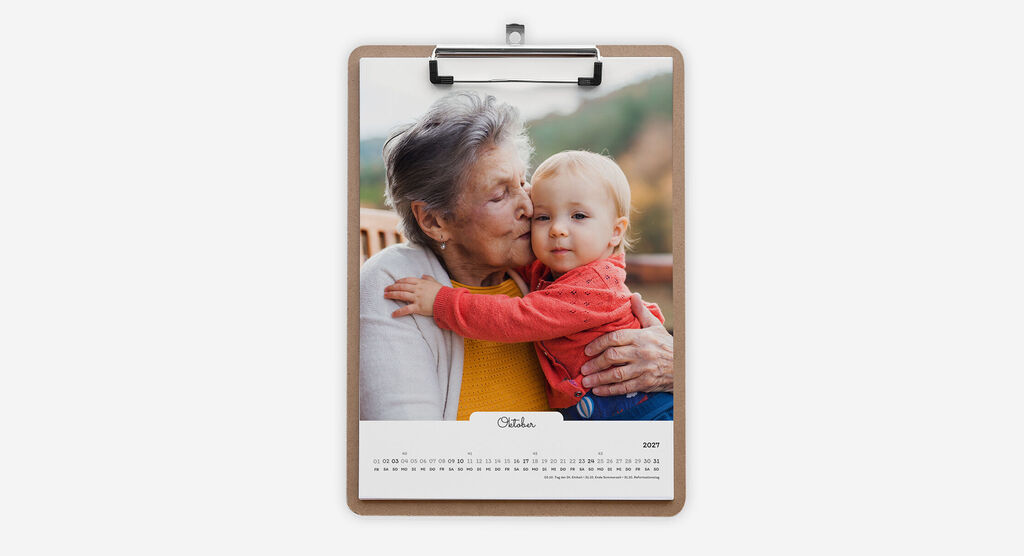 Kalender im A4-Hochformat mit einem Klemmbrett, weißem Design in handgeschriebenem Stil und Foto von Kleinkind mit Oma.