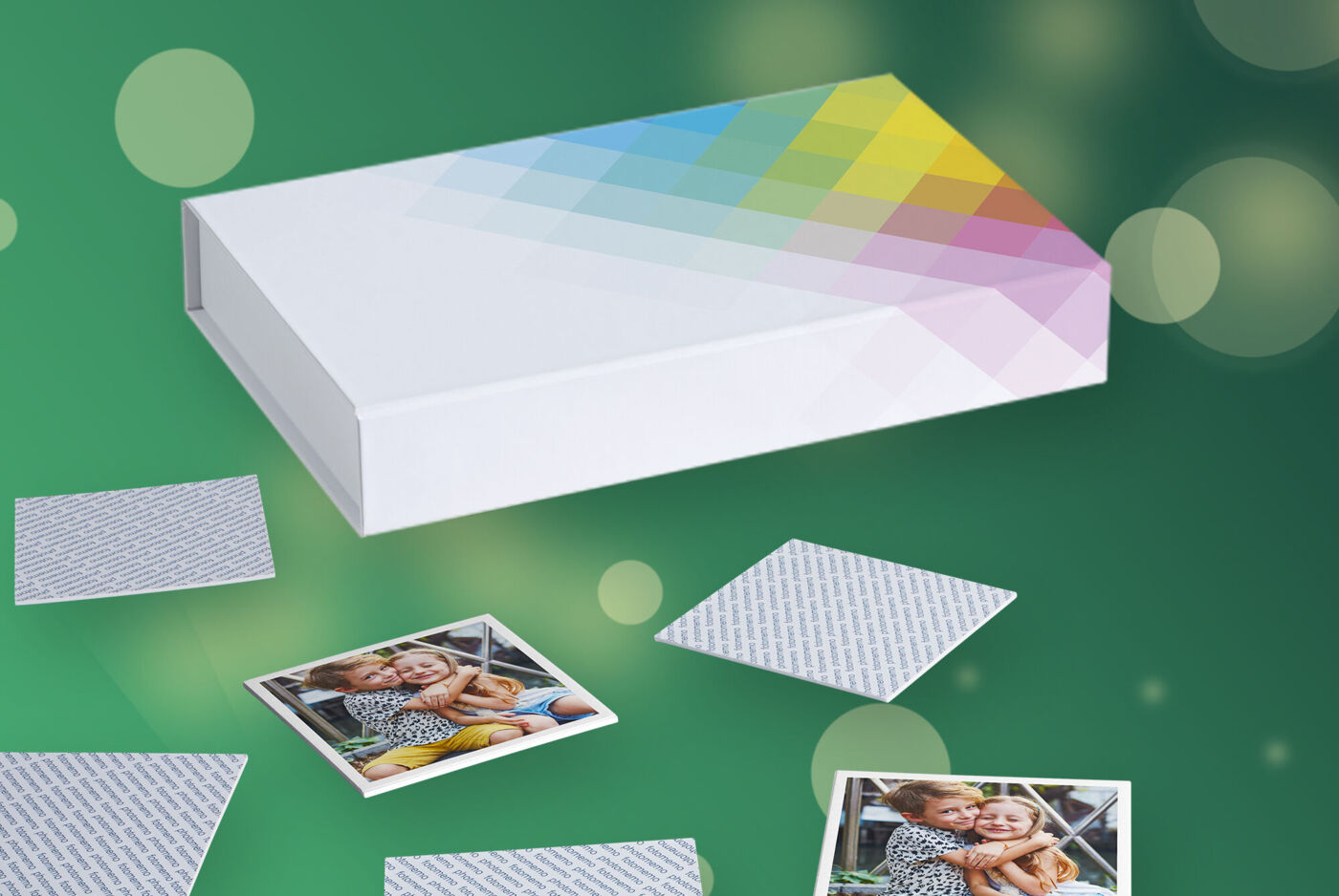 Memory Spiel mit Karten, die mit Kinderfotos bedruckt sind, vor einer weißen Schachtel mit buntem Design