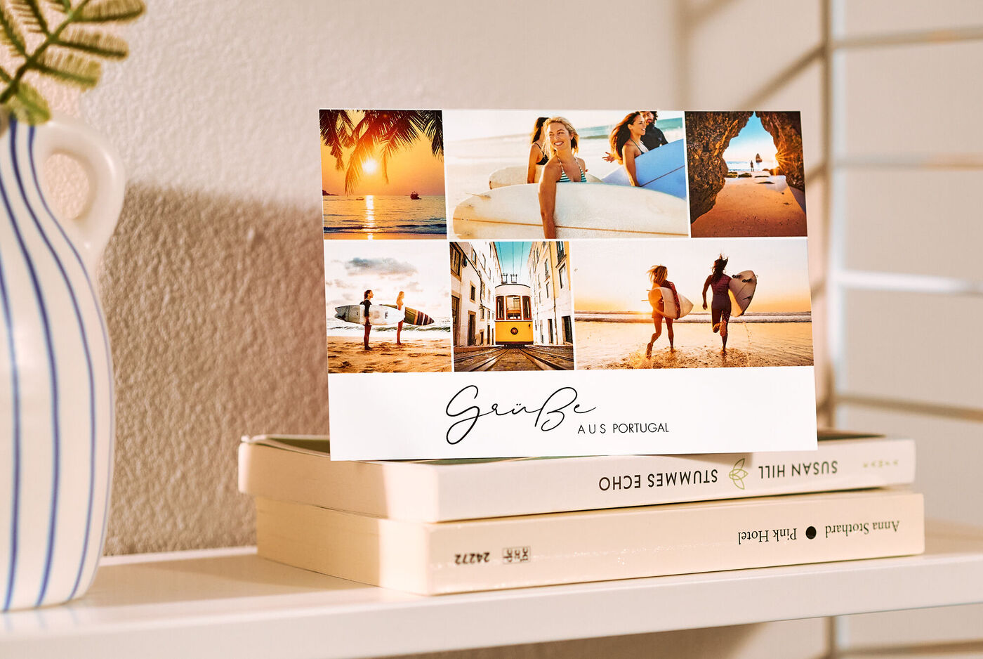 Eine Postkarte mit einer Collage aus Urlaubsfotos und dem Titel "Gruß aus Portugal" steht dekorativ auf einem Regal mit Büchern