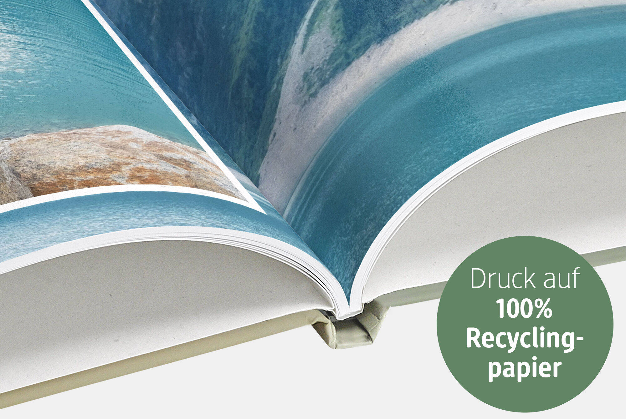 Offenes Fotobuch mit blauer Wasserlandschaft auf Recyclingpapier.