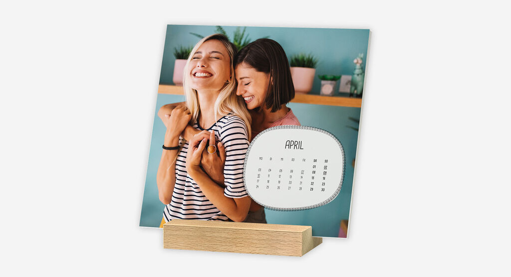 Kalender mit verspieltem Design und Foto von zwei Freundinnen steht frei in einem Holzstandfuß.